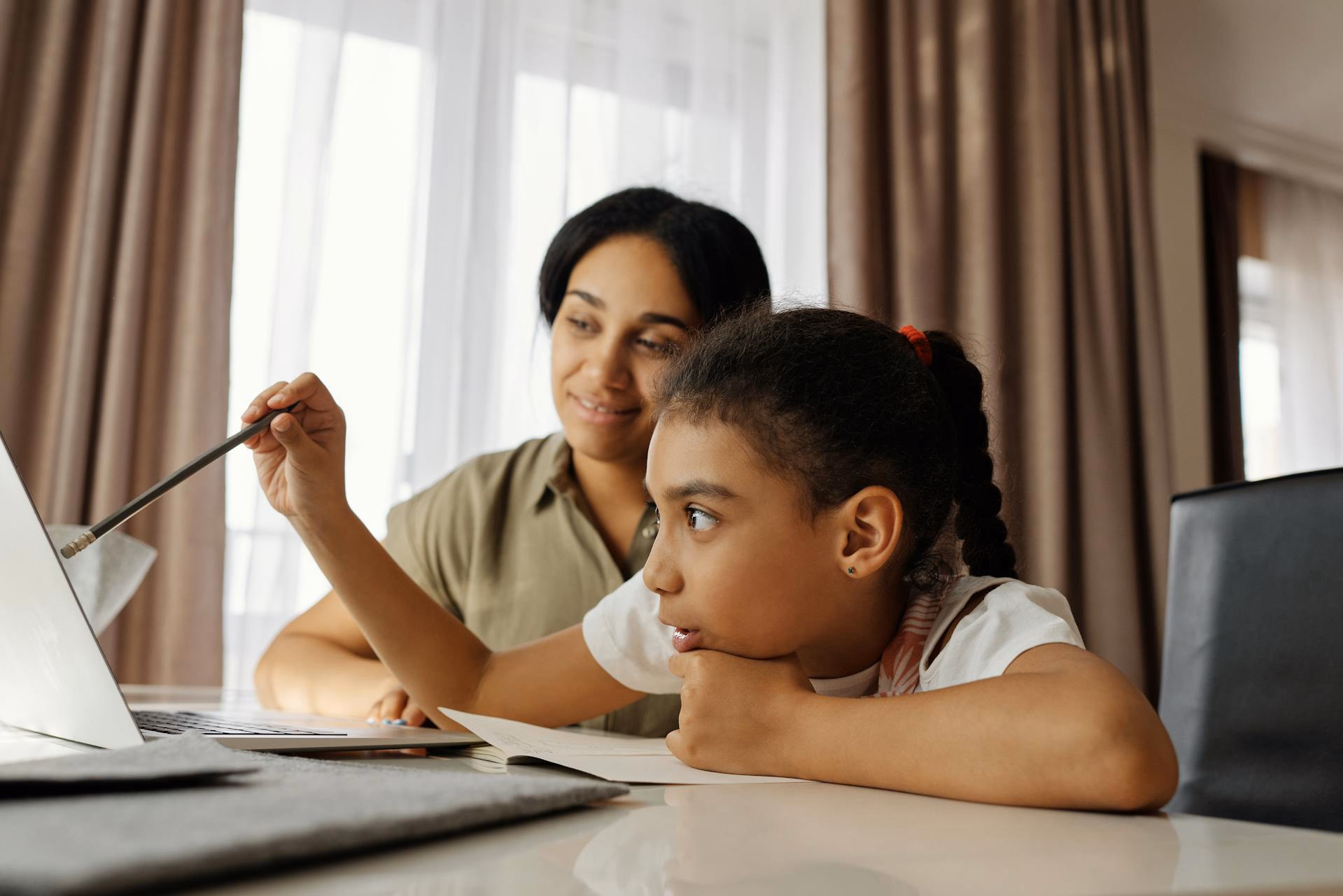 Parent and teenage daughter reviewing a telepsychiatry appointment together on a laptop