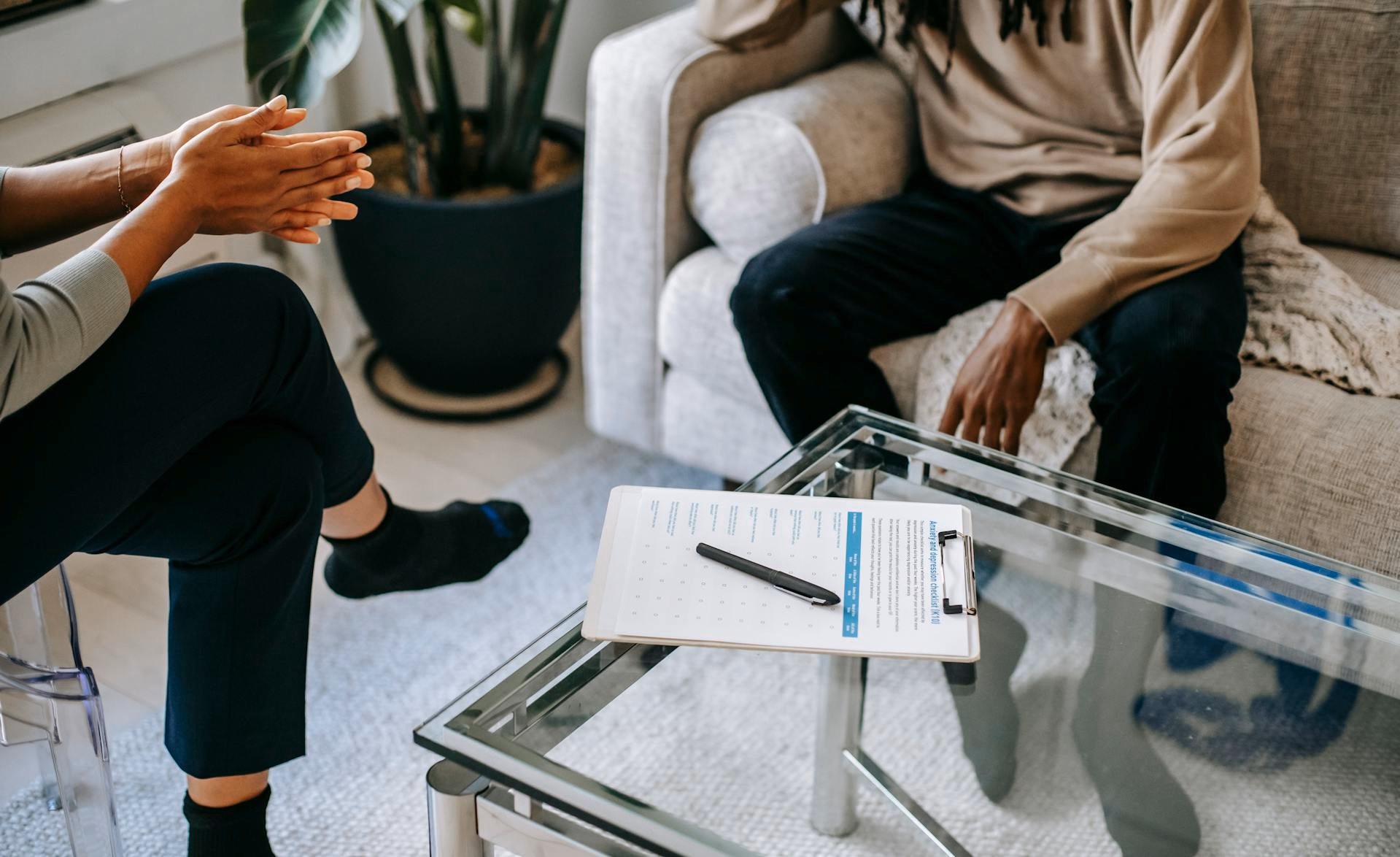 Clinician and patient talking in a bright sitting room with a clipboard on the coffee table