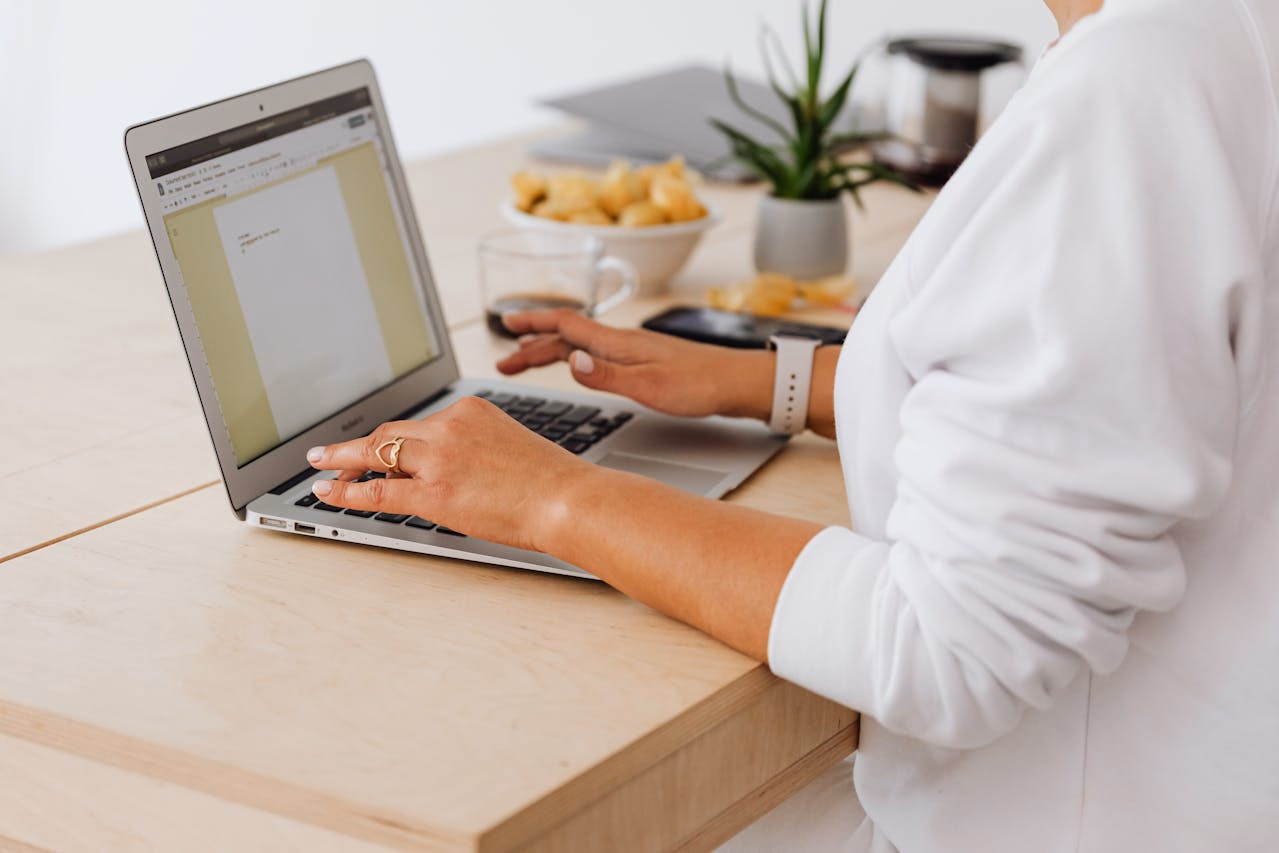 Patient at a wooden desk reviewing medication notes on a laptop beside a plant