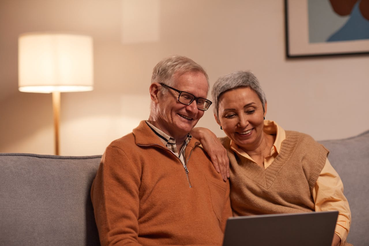 Older couple on a couch attending a virtual psychiatric appointment on a laptop together
